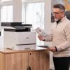 Man reviewing color documents printed from Brother MFC-L8930CDW all-in-one laser printer in home office
