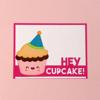 Greeting card with smiling cupcake wearing party hat and 'Hey Cupcake!' text