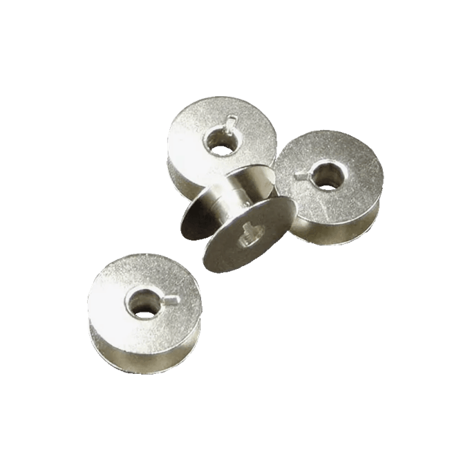 Four metal sewing machine bobbins on black background