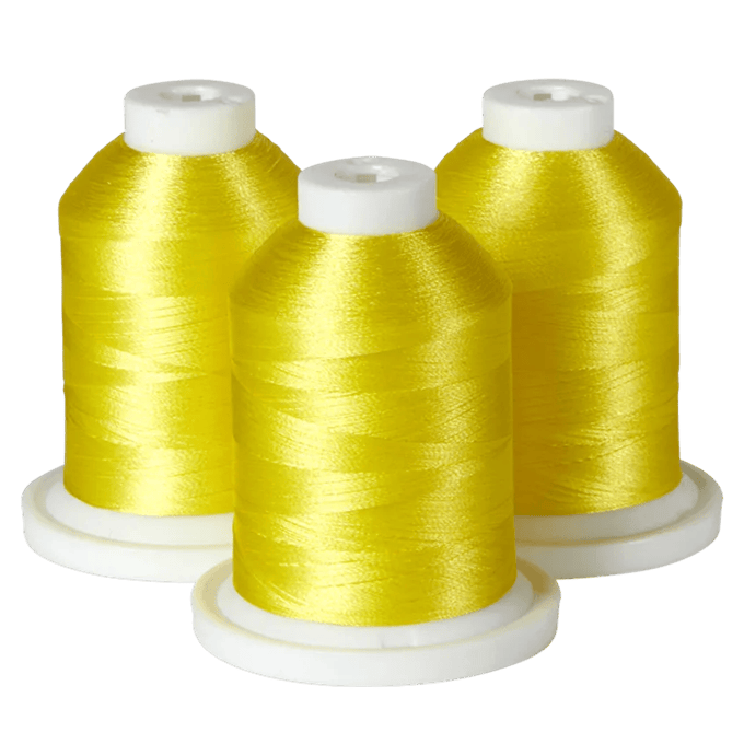Three spools of bright yellow Brother embroidery thread on white bases