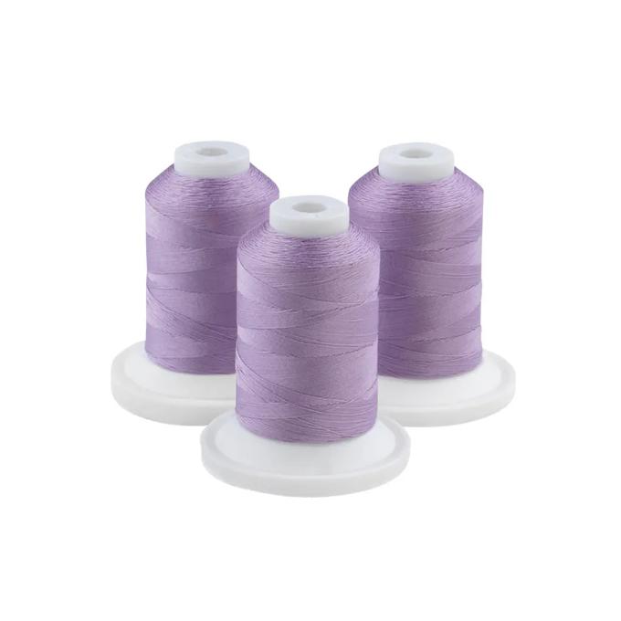 Three spools of mild purple embroidery thread on white bases