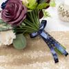 Bridesmaid bouquet with purple roses, greenery, and navy ribbon with gold lettering on sequin fabric