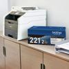 Brother all-in-one laser printer with TN221 2-pack toner cartridges on wooden desk