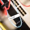 Brother label maker tape with Fibre-26 text on blue cable for industrial labeling