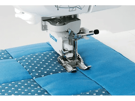 Brother sewing machine presser foot stitching blue quilted fabric with decorative pattern