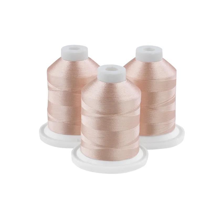 Three peach-colored embroidery thread spools on white bases
